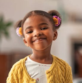 Abby's real photo — a smiling child in a yellow cardigan